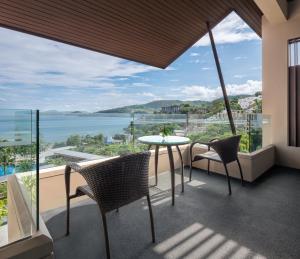 卡马拉海滩Hyatt Regency Phuket Resort - SHA Extra Plus的阳台配有桌椅,享有海景。