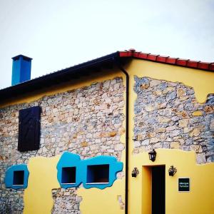 CarriazoAlbergue Casa Vacas的黄色的建筑,带有石墙
