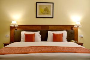 克久拉霍Greenwood Hotel的一间卧室配有一张带橙色枕头的大床