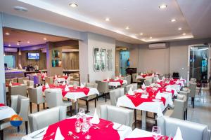 马普托Hotel Terminus Maputo的用餐室配有红色桌子和白色椅子