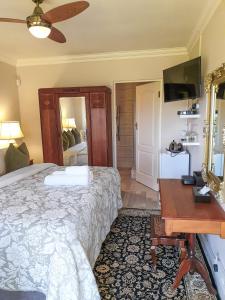 克拉格斯Elephant Country Guest House的一间卧室配有一张床、一张书桌和一面镜子