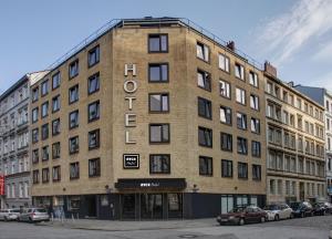 汉堡NYCE Hotel Hamburg City的街上一座大型砖砌建筑,有停车的汽车
