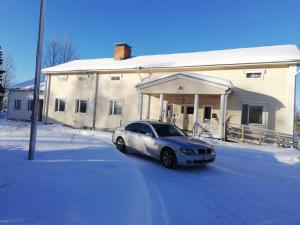凯尔赛迈基Kattilakosken vanha Pappila的雪中停在房子前面的汽车