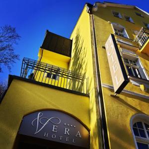 亚希莫夫Hotel Vera的黄色建筑,标有酒店标志
