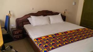 库马西Sign of Silence Hostel的一间卧室配有一张带彩色毯子的床