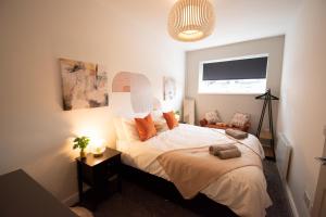 Ideal Lodgings in Walkden的一间卧室配有带白色床单和橙色枕头的床。