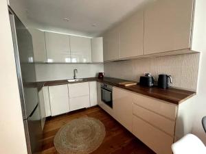 直布罗陀Stylish 2BR contemporary design perfect vacation的厨房铺有木地板,配有白色橱柜。