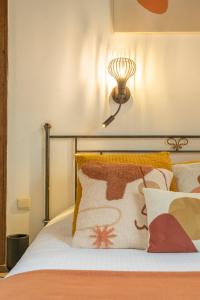 布鲁日运河景泰尔莱恩酒店的一张带橙色枕头的床和墙上的灯