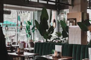 马斯特里赫特德拉布尔斯酒店的一间拥有绿色长凳、桌子和植物的餐厅