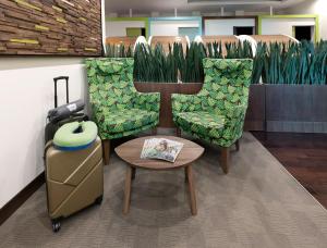 迪拜sleep 'n fly Sleep Lounge, A-Gates Terminal 3 - TRANSIT ONLY的一间房间,配有两把椅子、一张桌子和一个行李箱