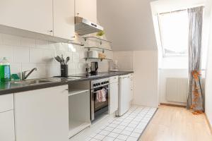 维也纳Vibrant Aparment perfect for Long Stays的厨房配有白色橱柜、水槽和炉灶。