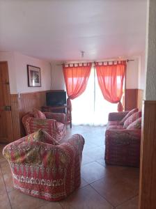安加罗阿Cabañas MANA NUI INN的客厅配有红色家具和大窗户
