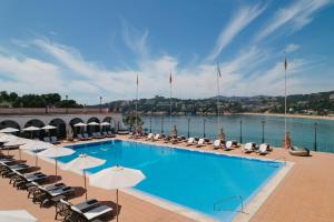 萨卡罗Hostal de la Gavina GL - The Leading Hotels of the World的一个带椅子和遮阳伞的大型游泳池