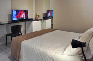 累西腓Suites Residence的卧室配有一张床,墙上设有两个显示器