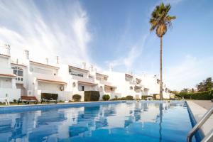 阿尔布费拉Oura Parque Apartamentos Turisticos的一座别墅,设有游泳池和棕榈树