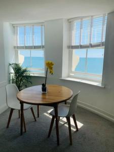 布莱顿霍夫Penthouse Sea view home的配有2扇窗户的客房内的一张木桌和椅子