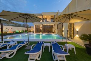 索瓦马Adam's Luxury Villa DeadSea的一个带蓝色和白色椅子及遮阳伞的游泳池