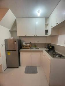 武端市Lily’s Homestay的厨房配有白色橱柜和不锈钢冰箱