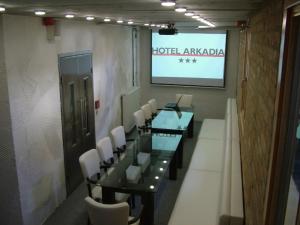 佩奇阿卡迪亚酒店的一间会议室,配有桌椅和屏幕