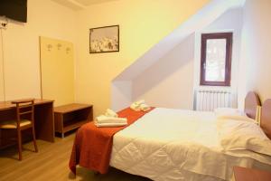 Prati di TivoHotel Gran Sasso的一间卧室配有一张床、一张书桌和一个楼梯