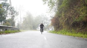 甘托克Yellow Sapphire, Premium Sikkimese Homestay的骑着自行车在雨中沿着公路骑行的人