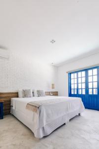 瓜鲁雅Pousada Villa Santô的白色卧室设有一张带蓝色门的大床