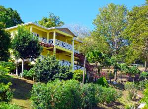 CharlotteSeascape Villa 2BR with Stunning Caribbean Sea View的一座黄色的房屋,位于一座树木和灌木丛的山丘上