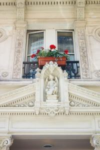 巴黎梅斯雷共和酒店的一座建筑,在阳台上有雕像,有红花