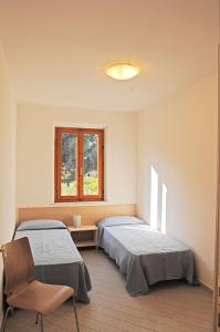 坎普码头卡萨皮内塔公寓酒店的一间卧室设有两张床、一把椅子和一个窗户。
