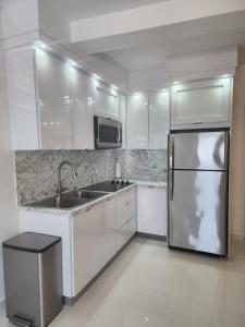 圣胡安San Juan Home的厨房配有白色橱柜和不锈钢冰箱