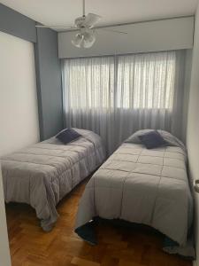 门多萨Departamento en peatonal Mendoza的一间卧室配有两张床和吊扇