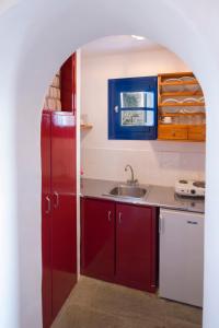 特里皮蒂Marketos Windmill and Houses的一间带红色橱柜和水槽的厨房