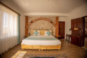 乌奇希萨尔Soleado Cappadocia Hotel的一间卧室设有一张带砖墙的大床