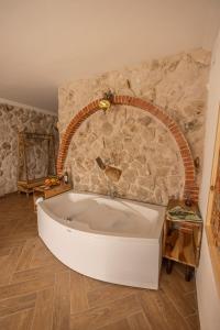 乌奇希萨尔Soleado Cappadocia Hotel的石墙客房内的浴缸