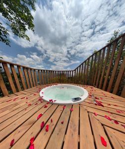 BelénFinca Hotel Tierra Verde的铺有红色花瓣的木质甲板上的热水浴池