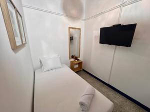 麦德林Hostal Casa Guadalupe的白色的客房配有床和平面电视。