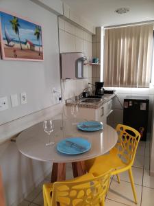 纳塔尔Janastí Suítes Praia de Ponta Negra的厨房配有桌子和2把黄色椅子