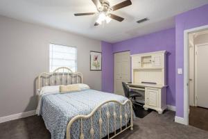 坦帕EntireHouse w/Bush Garden View_Private Heated POOL的一间卧室设有紫色的墙壁、一张床和一张书桌