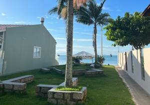弗洛里亚诺波利斯Ilha Forte Praia Hotel的一座白色的建筑,长凳和棕榈树环绕着大海