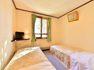 茅野車山高原悠莱旅馆的一间卧室设有两张床和窗户。