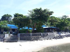 美娜多Bunaken Sunrise Beach的一座拥有石墙和树木的度假村