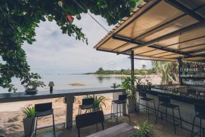 苏梅岛Chill Inn Lamai Hostel & Beach Cafe的一个带椅子的酒吧,享有海滩美景