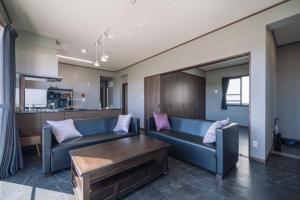 Hanagusukuプライベートハウス ぅーじ家的客厅配有蓝色的沙发和桌子