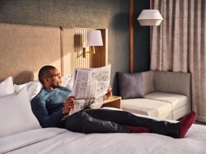 罗斯芒特Holiday Inn Chicago O'Hare - Rosemont, an IHG Hotel的坐在床上看报纸的人