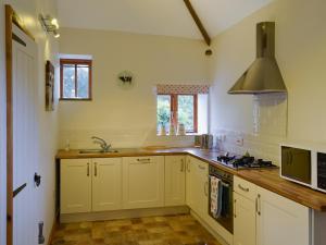BlofieldThe Cowshed的厨房配有白色橱柜、水槽和炉灶。