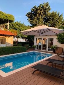 杜布罗夫尼克Villa Gloria 2的一个带遮阳伞和两张躺椅的游泳池