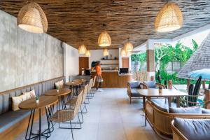 坎古Roomates Hostel Canggu by Ini Vie Hospitality的餐厅设有木制天花板和桌椅