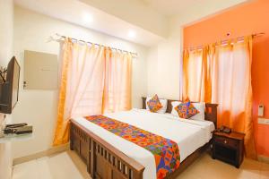 KondapurFabHotel Corner Courtyard的一间卧室配有带橙色窗帘的大床