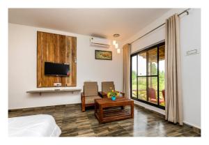 塔拉Grand Narmada Homestay Resort-Bandhavgarh的一间卧室配有一张床、一台电视和一张桌子