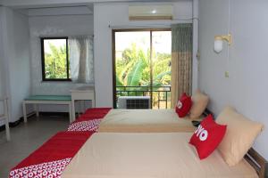 清迈OYO 75420 Howto Hotel的一间卧室配有两张带红色枕头的床和窗户。